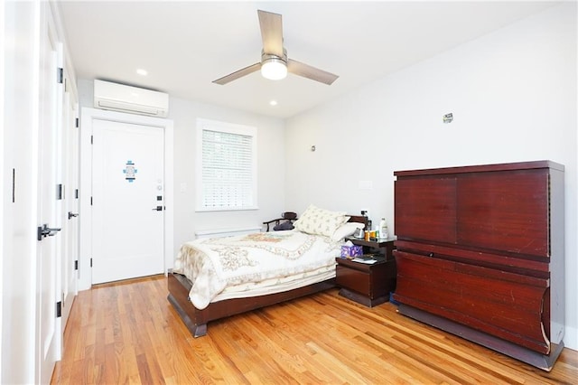 bedroom featuring ceiling fan, light wood-type flooring, and a wall unit AC