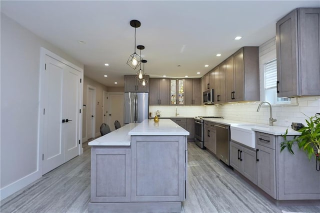 kitchen with pendant lighting, a center island, sink, light hardwood / wood-style floors, and stainless steel appliances