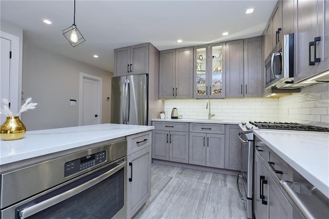 kitchen featuring tasteful backsplash, sink, pendant lighting, and appliances with stainless steel finishes