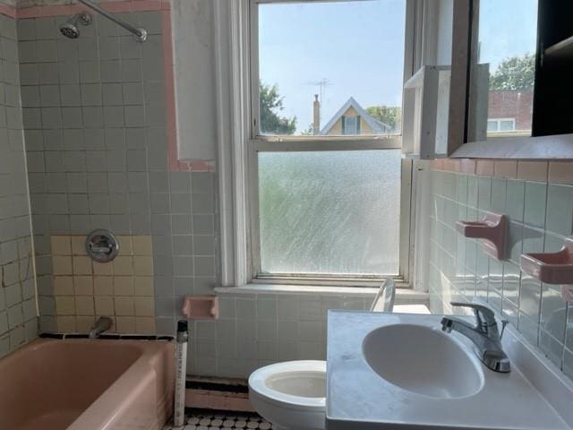 full bathroom featuring a baseboard radiator, a healthy amount of sunlight, and tile walls