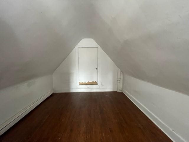 additional living space with lofted ceiling, dark hardwood / wood-style flooring, and a baseboard heating unit