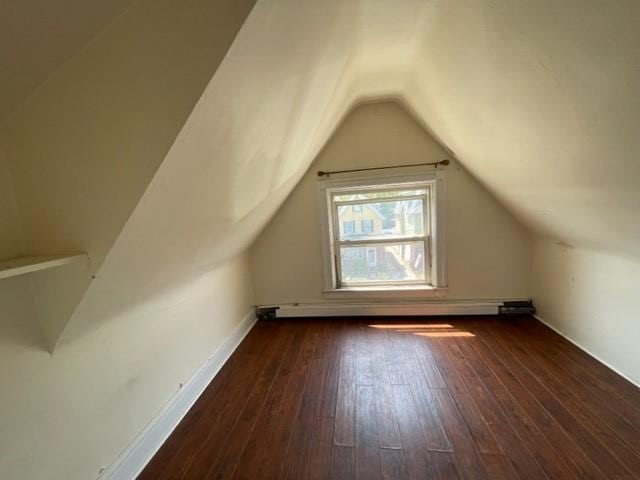 additional living space with a baseboard heating unit, vaulted ceiling, and dark hardwood / wood-style floors