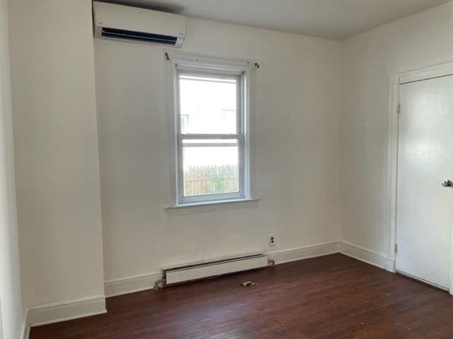 empty room with a baseboard heating unit, dark hardwood / wood-style floors, and a wall mounted AC