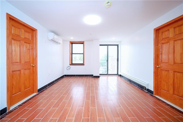 spare room with a baseboard radiator, baseboards, wood finished floors, and a wall mounted air conditioner