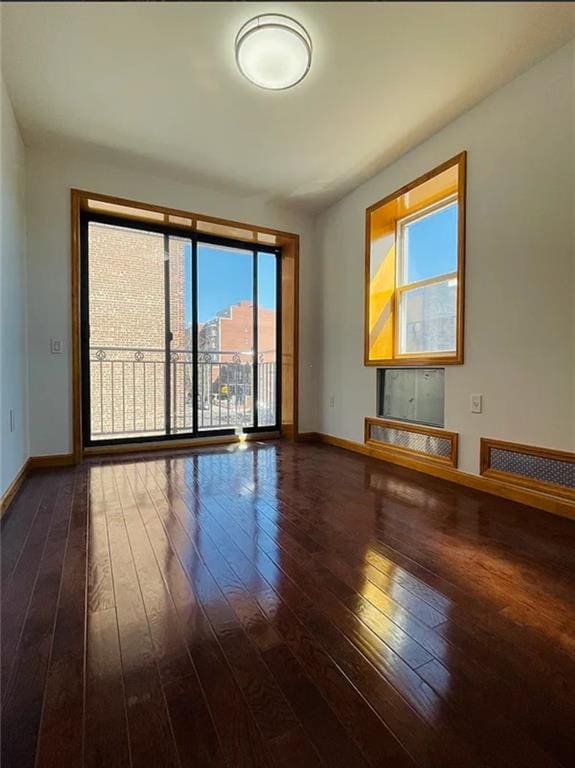 empty room with visible vents, baseboards, and dark wood-style flooring