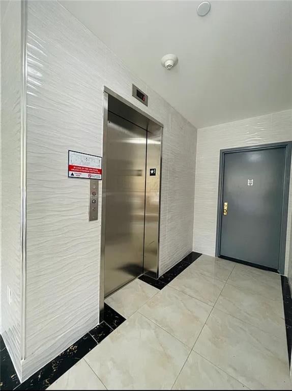 hallway featuring tile walls and elevator