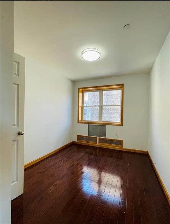 unfurnished room with hardwood / wood-style flooring and baseboards