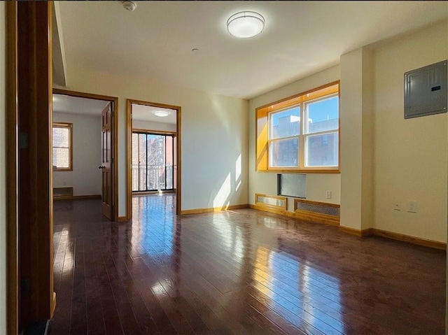 unfurnished room featuring dark wood-style flooring, electric panel, and baseboards