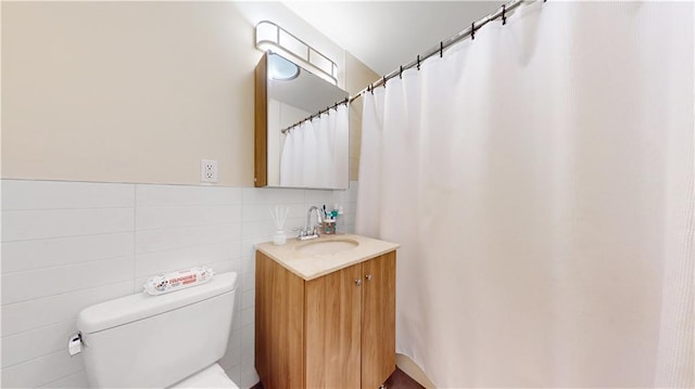 bathroom featuring toilet, tile walls, and vanity