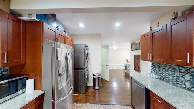 kitchen featuring stainless steel appliances, stacked washer / drying machine, decorative backsplash, and light stone counters