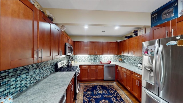 kitchen with light stone counters, recessed lighting, backsplash, appliances with stainless steel finishes, and a sink