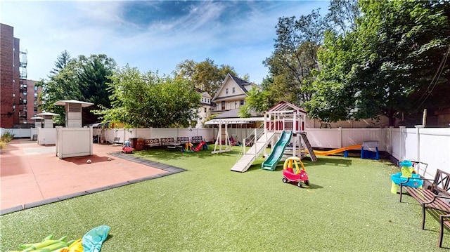 view of playground with a patio area, a fenced backyard, and a lawn