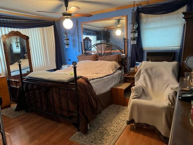 bedroom with a ceiling fan, cooling unit, and wood finished floors