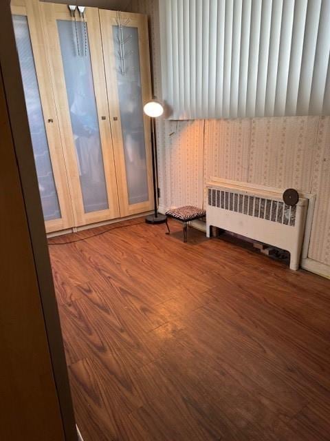 unfurnished bedroom featuring radiator heating unit and wood finished floors