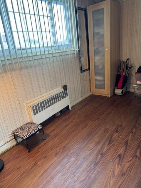 interior space featuring radiator, wallpapered walls, and wood finished floors