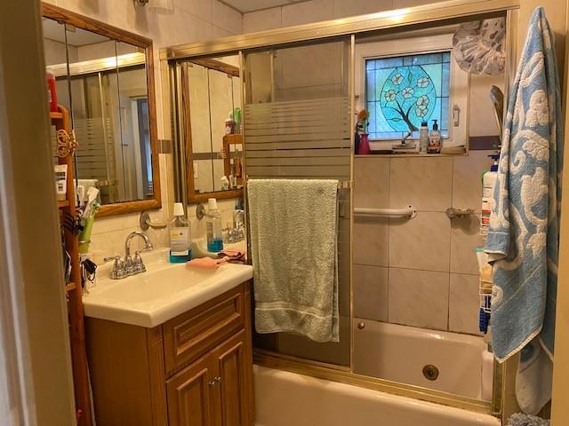 full bathroom featuring enclosed tub / shower combo and vanity