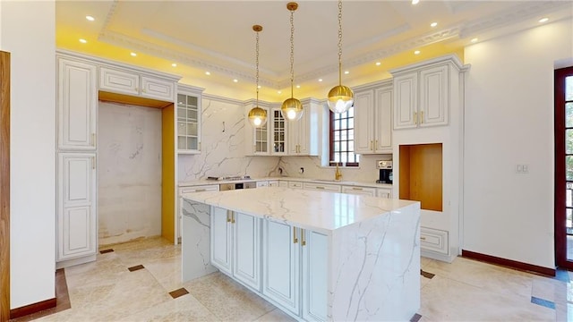 kitchen with a kitchen island, a raised ceiling, white cabinetry, and hanging light fixtures