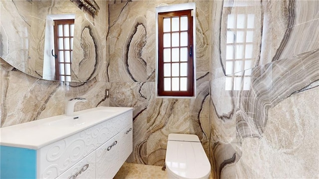 bathroom with vanity, toilet, and tile walls