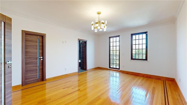 empty room featuring hardwood / wood-style flooring, crown molding, and a notable chandelier