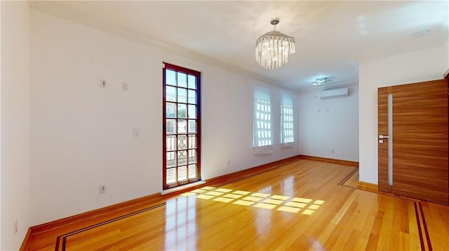 empty room featuring a wall mounted AC, crown molding, a notable chandelier, and hardwood / wood-style flooring