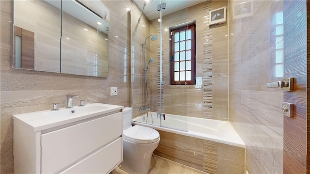 full bathroom featuring vanity, tiled shower / bath combo, toilet, and tile walls