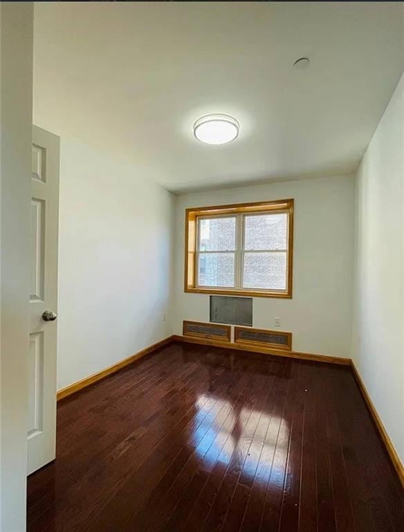 unfurnished room with baseboards and dark wood-style flooring