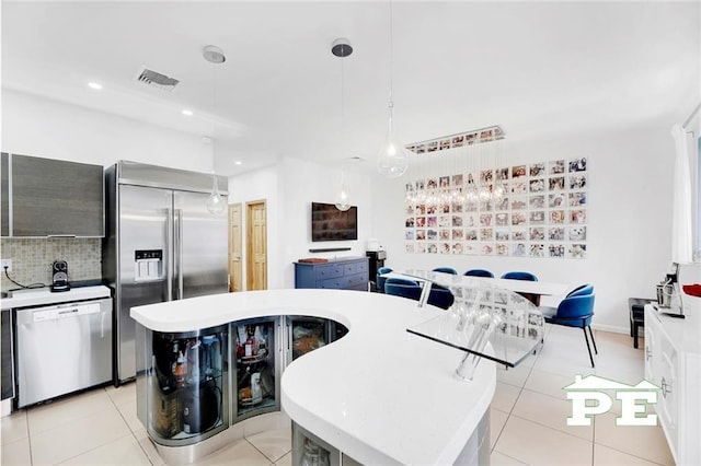 kitchen with appliances with stainless steel finishes, a center island, light tile patterned floors, and hanging light fixtures