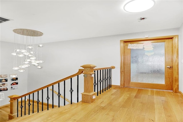 hallway with hardwood / wood-style floors and a chandelier