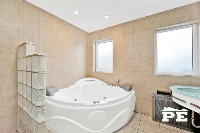 bathroom featuring tile patterned flooring, a bathtub, plenty of natural light, and tile walls