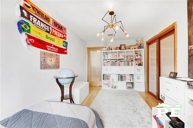 bedroom with an inviting chandelier and light hardwood / wood-style flooring