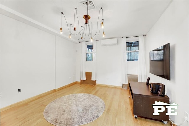 interior space featuring plenty of natural light, wood-type flooring, a wall mounted air conditioner, and a notable chandelier