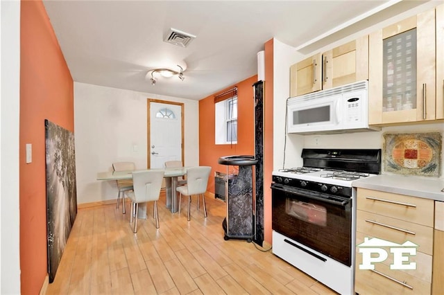 kitchen featuring light brown cabinetry, light hardwood / wood-style flooring, and white appliances