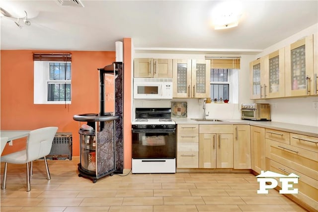 kitchen with radiator heating unit, sink, white appliances, light brown cabinetry, and light wood-type flooring