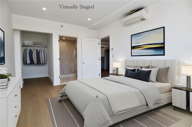 bedroom featuring baseboards, connected bathroom, wood finished floors, an AC wall unit, and recessed lighting