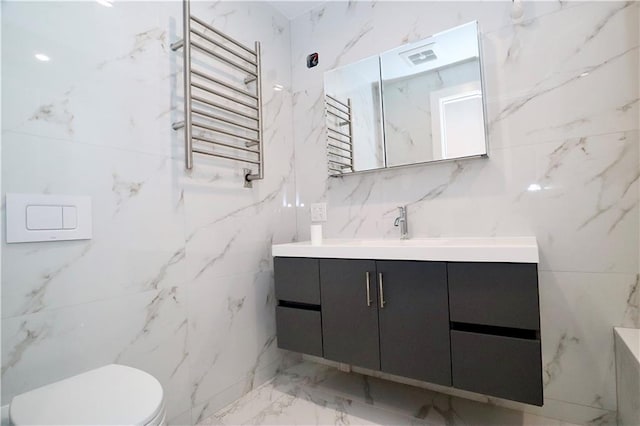 full bathroom with radiator, toilet, marble finish floor, vanity, and stone wall