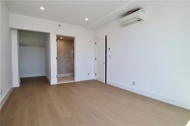 unfurnished bedroom with recessed lighting, wood finished floors, baseboards, and a wall mounted AC