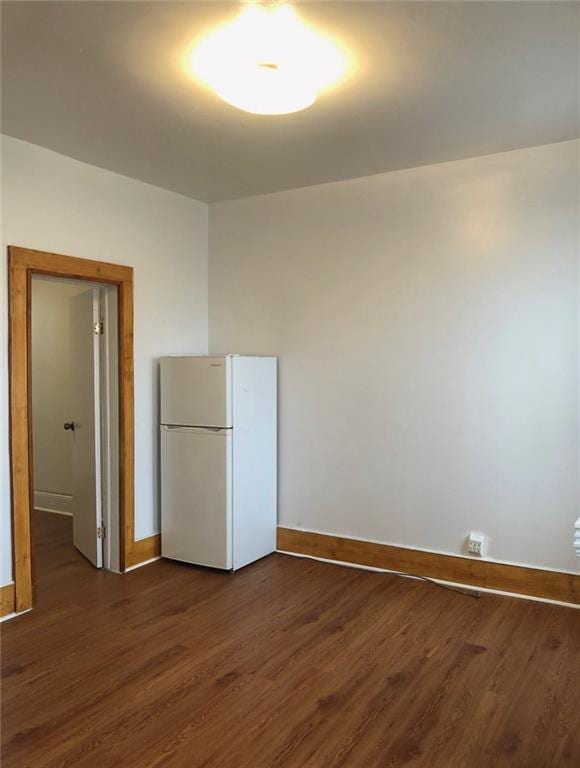 unfurnished room with dark wood finished floors and baseboards