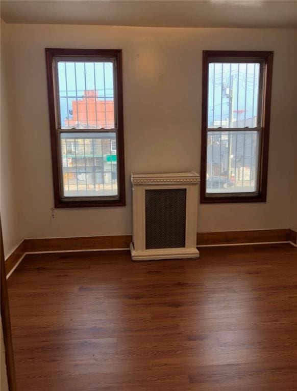 unfurnished living room featuring plenty of natural light, baseboards, and wood finished floors