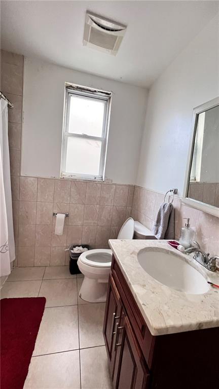 bathroom featuring tile patterned floors, toilet, tile walls, and vanity