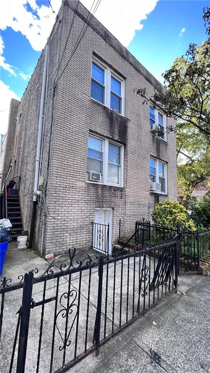 view of front facade with brick siding, cooling unit, and a fenced front yard