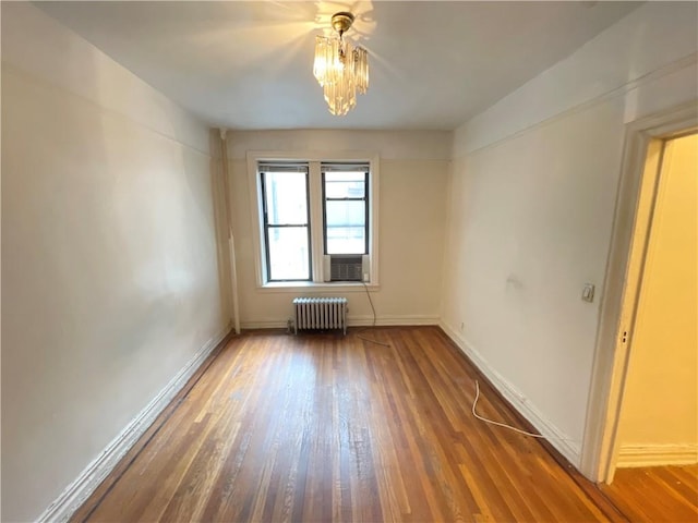 spare room featuring radiator and dark hardwood / wood-style floors