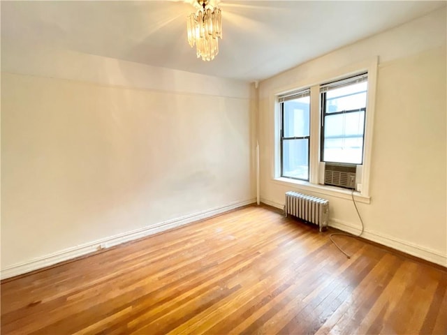 empty room with cooling unit, light hardwood / wood-style flooring, and radiator heating unit