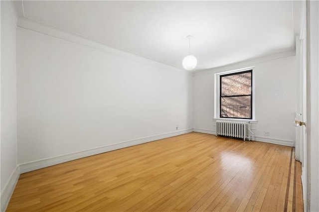 unfurnished room featuring radiator heating unit, baseboards, light wood-type flooring, and ornamental molding