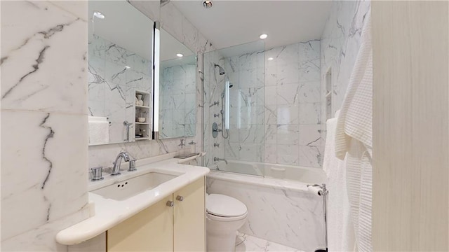 full bathroom with vanity, toilet, tiled shower / bath, and tile walls