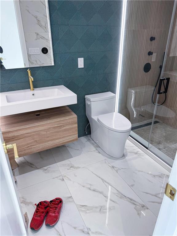 bathroom with vanity, toilet, tile walls, and walk in shower