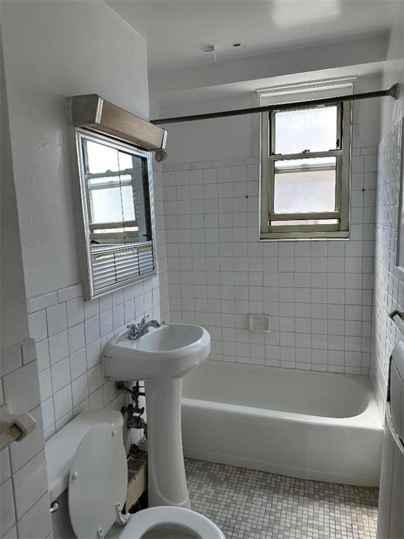 bathroom with a wealth of natural light, toilet, and tiled shower / bath