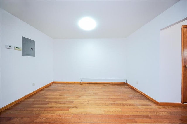 empty room with light wood-type flooring, electric panel, and a baseboard radiator