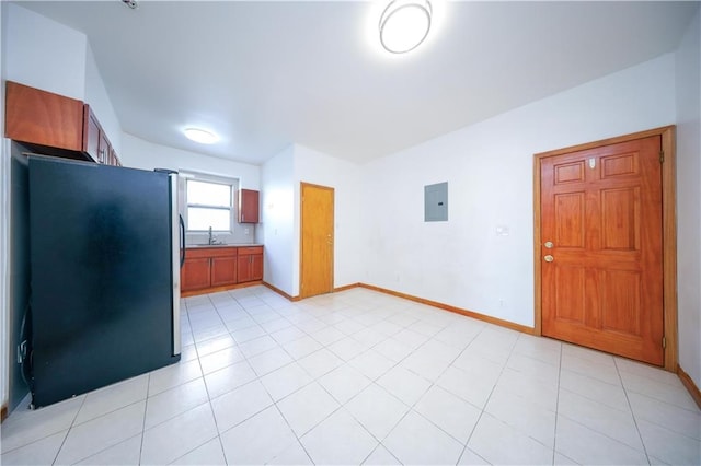 kitchen featuring electric panel, sink, stainless steel refrigerator, and light tile patterned flooring