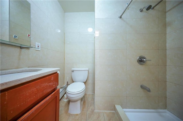 bathroom featuring toilet, a baseboard radiator, a tile shower, tile walls, and vanity