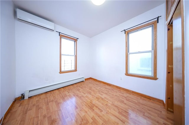 spare room with light hardwood / wood-style flooring, a wall mounted air conditioner, and baseboard heating